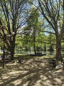 a park with a boat on the water and trees at Camping Magali Plage in Liourdres