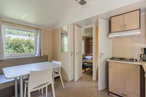a small kitchen and dining room with a table and chairs at Mobil-home - Le 147 aux Iscles in La Roque-dʼAnthéron +11 photos