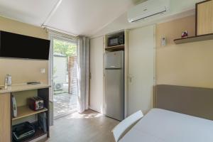 a small room with a bed and a tv and a refrigerator at Mobil-home - Le 147 aux Iscles in La Roque-dʼAnthéron