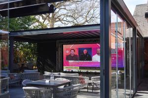 a screened in patio with tables and a screen at Draycote Hotel And Whitefields Golf Course in Rugby