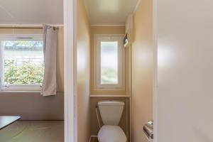 a bathroom with a toilet and two windows at Mobil-home - Le 147 aux Iscles in La Roque-dʼAnthéron