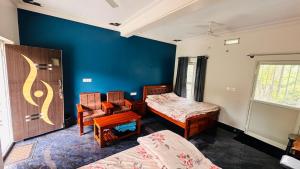 a bedroom with two beds and a blue wall at Sapthagiri Streamways in Madikeri
