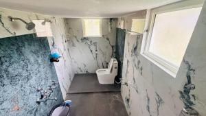 a small bathroom with a toilet and a window at Sapthagiri Streamways in Madikeri