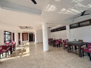 ein Esszimmer mit Tischen, Stühlen und Fenstern in der Unterkunft Hotel B Wings in Tādong