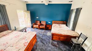 a room with two beds and chairs and a blue wall at Sapthagiri Streamways in Madikeri