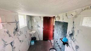 a bathroom with white marble walls and a red door at Sapthagiri Streamways in Madikeri