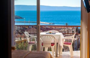 een tafel en stoelen op een balkon met uitzicht op de oceaan bij City Apartment Mima in Makarska