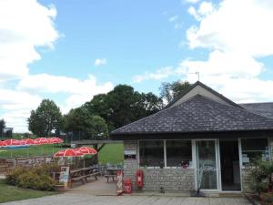 a building with tables and umbrellas in a park at Camping 3 étoiles - Piscine - ccbgaci in Illiers