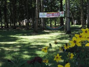 a sign in a park with trees and yellow flowers at Camping 3 étoiles - Piscine - ccbgaci in Illiers
