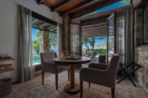 a dining room with a table and chairs and large windows at Valeni Boutique Hotel & Spa in Portaria