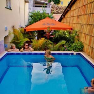 un grupo de personas en una piscina con sombrilla en Hostel Galeria 13, en Salvador