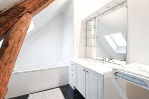 a white bathroom with a sink and a mirror at Gîte Lilas de mer in Ponthoile