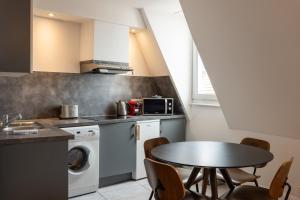a kitchen with a table and a washing machine at Downtown by Max, Refuge in city center in Mulhouse +14 photos