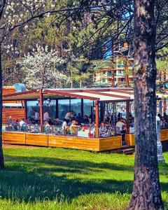 a restaurant with people sitting at tables in a park at One Luxury Suites AKUSTIK - 3 minuta peške do Jezera in Zlatibor