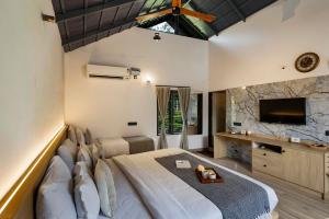 a bedroom with a large bed and a flat screen tv at Avocado Cottages by Alaya Stays, Coorg in Suntikoppa
