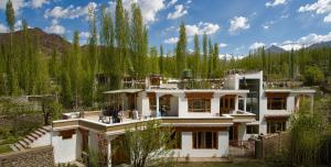 a large white house in the middle of a forest at Glacier View Guest House in Leh