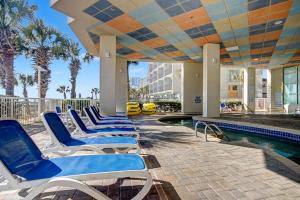 a row of blue lounge chairs next to a swimming pool at Carolinian Beach Resort in Myrtle Beach