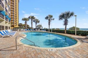 a swimming pool with chairs and palm trees at Carolinian Beach Resort in Myrtle Beach