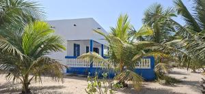 a blue and white house on the beach with palm trees at Baafeh in Sanyang