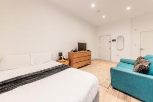 a bedroom with a bed and a blue couch at Sleeps 2 - Central - Studio - WiFi - Paid Parking in Maidstone
