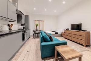 a living room with a blue couch and a kitchen at Sleeps 2 - Central - Studio - WiFi - Paid Parking in Maidstone