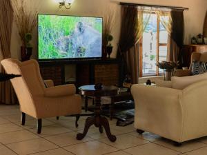 a living room with two chairs and a tv at PHAKELA PRIVATE LODGE in Thabazimbi