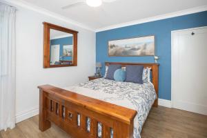 a bedroom with a bed with blue walls and a mirror at BJ Mick's Lakefront Apartment in Forster