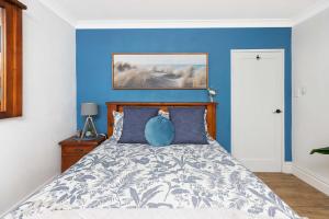 a bedroom with a bed with a blue wall at BJ Mick's Lakefront Apartment in Forster