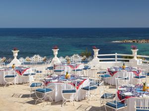 a group of tables and chairs with the ocean in the background at Hotel Mongibello Ibiza in Santa Eularia des Riu
