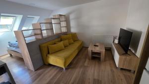 a living room with a yellow couch and a television at Apartmany CityCentrum Trencin in Trenčín