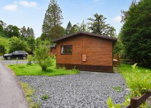 a cabin in the woods with a car parked next to it at Garth Holiday Park in Machynlleth