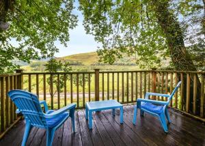 two blue chairs and a table on a deck at Garth Holiday Park in Machynlleth