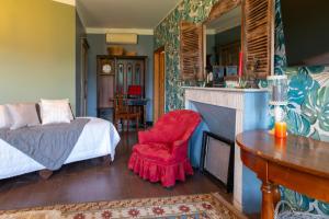 a bedroom with a bed and a red chair and a fireplace at Maison D'hôtes Casa Ghjunca in Rapale
