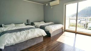 a bedroom with two beds and a large window at Sauna villa uchiumi in Uchiumi