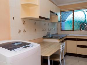 a kitchen with a washing machine and a wooden table at Zakumi Guesthouse in Kokstad