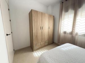 a bedroom with a bed and a wooden cabinet at Elegante Apartamento de 1 Dormitorio en Nerja in Nerja