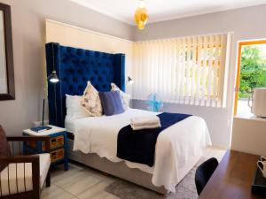 a bedroom with a bed with a blue headboard at Zakumi Guesthouse in Kokstad +103 photos