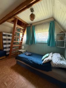 a bedroom with a bed with blue sheets and blue curtains at Tleniowo Domek in Tleń