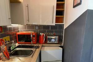 a kitchen with a sink and a red microwave at Studio - Parking - Garden - WiFi - Sleeps 2 in Cambridge