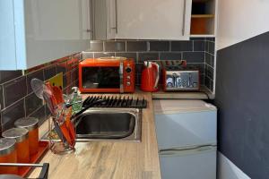 a kitchen with a sink and an orange microwave at Studio - Parking - Garden - WiFi - Sleeps 2 in Cambridge