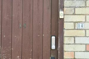 a wooden door with a remote control next to a brick wall at Studio - Parking - Garden - WiFi - Sleeps 2 in Cambridge