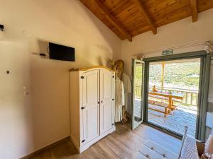 a living room with a tv and a sliding glass door at Elaia Rest House Retreat in nature in Fréngaina