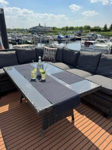 Ein Tisch auf einer Terrasse mit Sofa und Getränken in der Unterkunft Hausboot KOMET Luxus und Natur pur max 5 Pers in Maasbommel