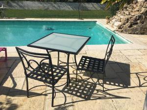 een glazen tafel en 2 stoelen naast een zwembad bij B&B Charming Saint Paul de Vence in Saint-Paul-de-Vence