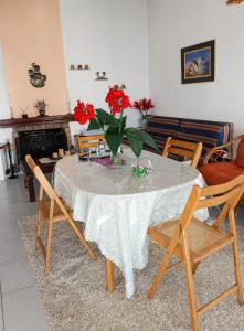 a dining room table with a vase of red flowers on it at Vicky's Sweet Home - Seaside Retreat in Evia in Agia Anna