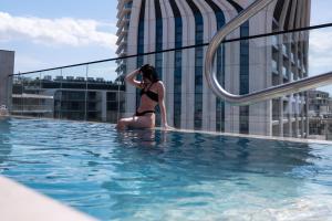 Eine Frau im Bikini sitzt in einem Schwimmbecken in der Unterkunft VITA Hotel & Rooftop in St Julian's