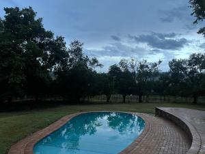 a swimming pool in a field with trees in the background at Valley Croft Farm in Hekpoort