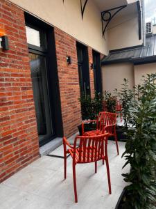 two red chairs sitting on a patio next to a building at Room 44 Garden 1 in Osijek