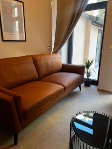 a brown couch in a living room with a table at Room 44 Garden 1 in Osijek