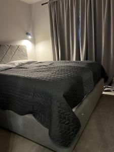 a bed with a black comforter in a bedroom at Room 44 Garden 1 in Osijek